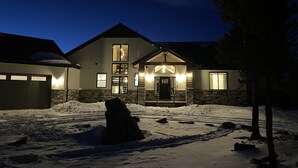 Ein zweistöckiges Haus mit Natursteinfassade, einer Garage und einer eisbedeckten Auffahrt.
