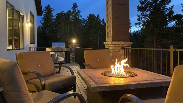 Eine Terrasse im Freien mit Feuerstelle, Sitzgelegenheiten und Grill.