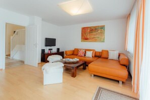 A modern living room with a sofa, a coffee table, and a television. - Offers space for up to 8 people Chalet Solymont by MoniCare in a quiet and sunny location (Seefeld)