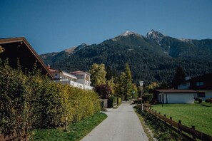 A mountain road leading to a residential area with houses, a clear sky, and a mountain in the background. - Offers space for up to 8 people Chalet Solymont by MoniCare in a quiet and sunny location (Seefeld)