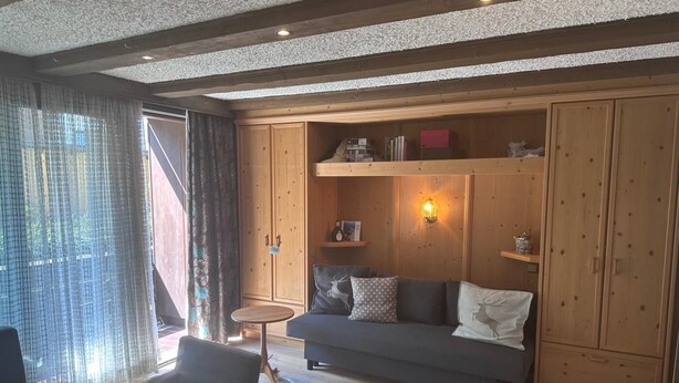 Una sala de estar acogedora con un sofá, una mesita redonda y armarios de madera.