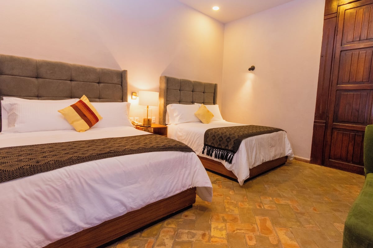 A double room with two beds, a wooden wardrobe, and a green chair.