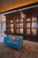 Una habitación con un sofá azul, un armario de madera con puertas de vidrio y techo de ladrillo.