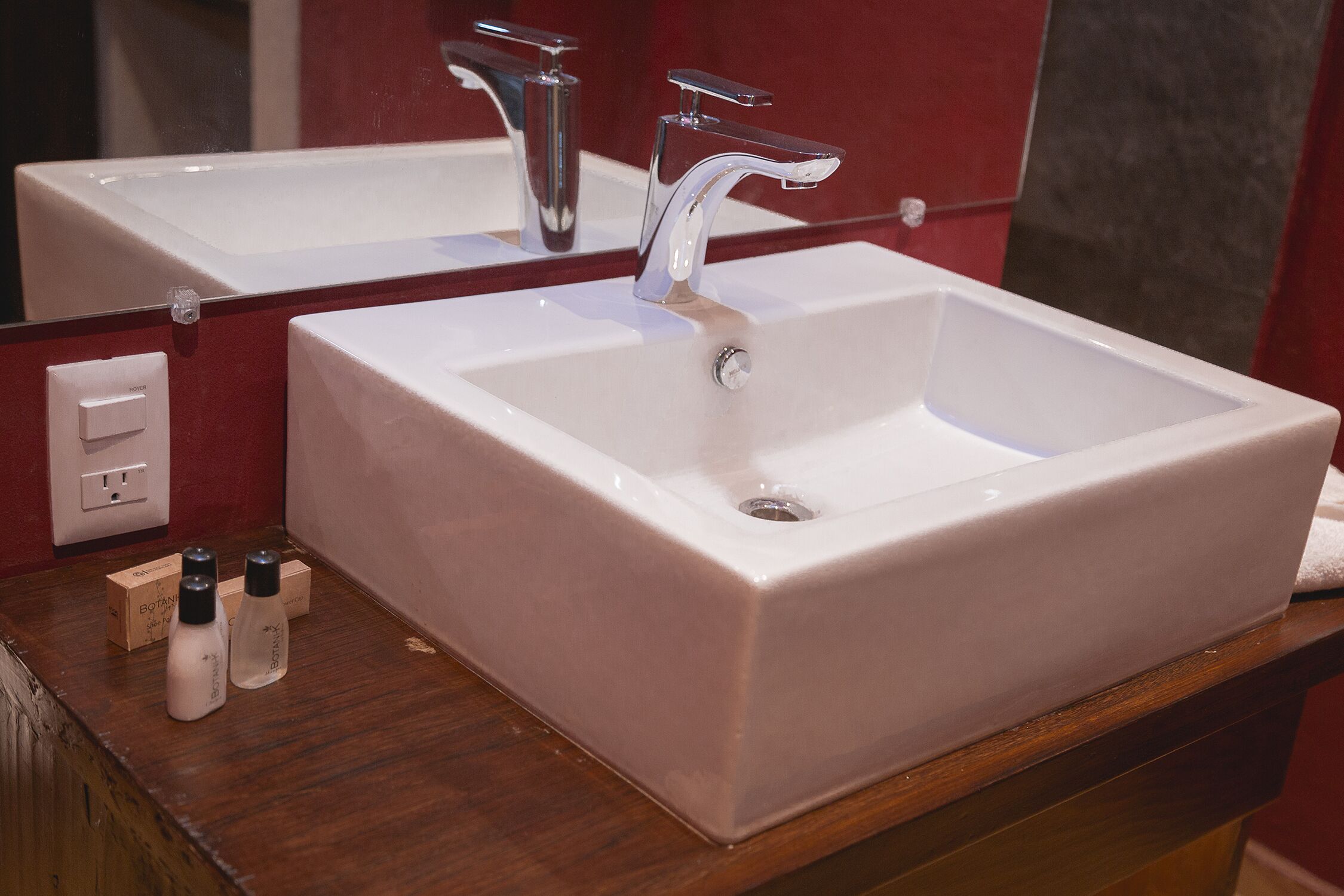 Un baño con un lavabo blanco, un espejo y una encimera de madera.