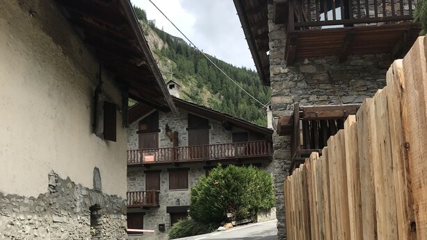 A narrow street flanked by traditional stone buildings with wooden balconies and a wooden fence. - Fascinating views of Mont Blanc (Courmayeur)