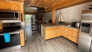 Eine Küche mit Holzausstattung, Edelstahlgeräten, einer Wendeltreppe und einem Wasserspender.