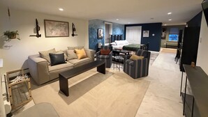 Una sala de estar moderna con sofá, sillones, una mesa de centro y un comedor con mesa y sillas.