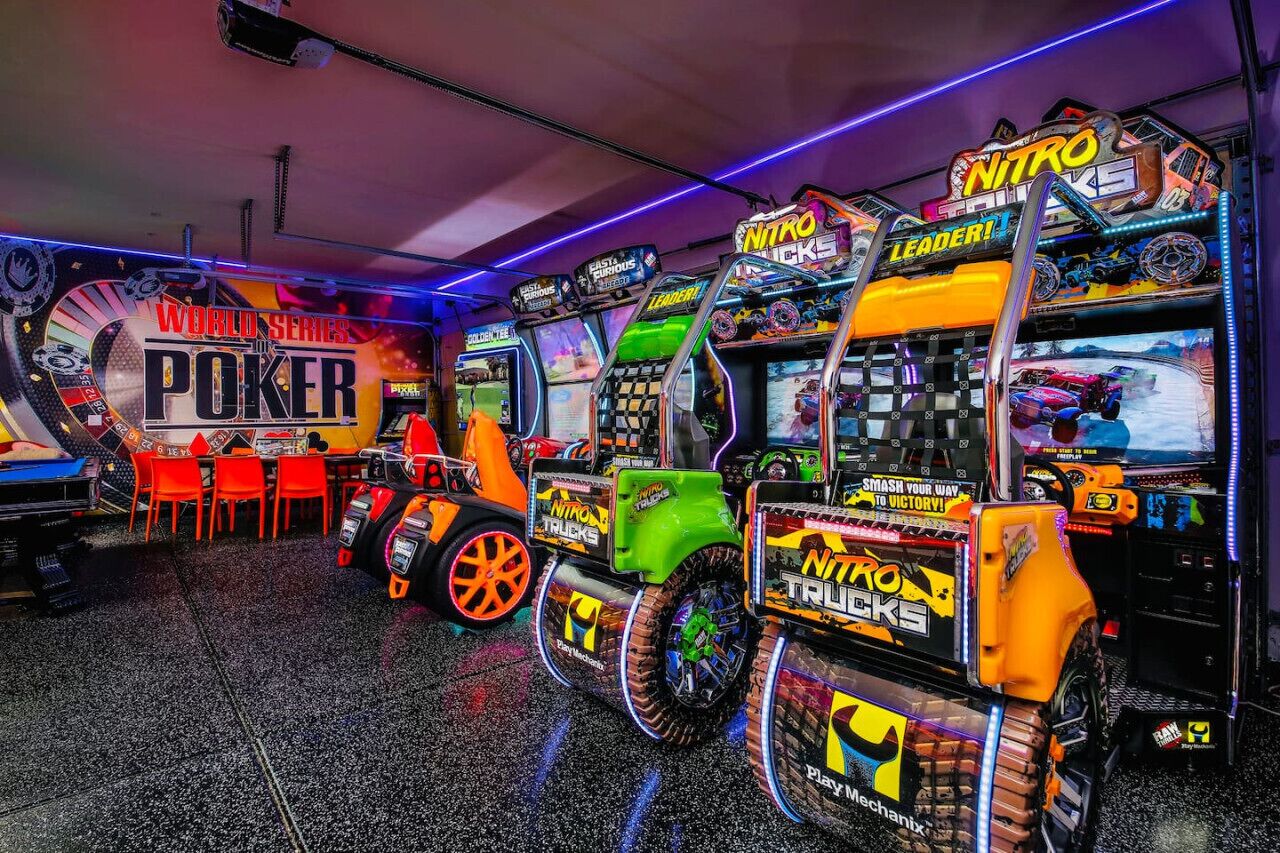Eine Spielhalle mit verschiedenen Spielautomaten, darunter ein auffälliges Spiel namens 'Nitro Trucks' und ein Schild mit 'World Series of Poker'.