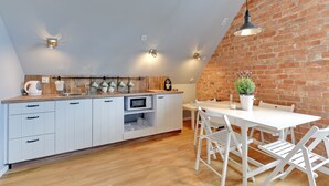 Eine Küche mit weißen Schränken, einer Holz Arbeitsplatte und einem Essbereich mit weißen Stühlen und einem Tisch.