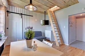 Ein modernes Interieur mit Esstisch, Sofa, Wand-Fernseher und einer Holzleiter.