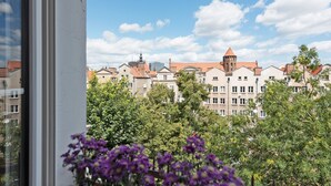 Ein Gebäude mit einem Turm und zahlreichen Fenstern, umgeben von Bäumen und Blumen.