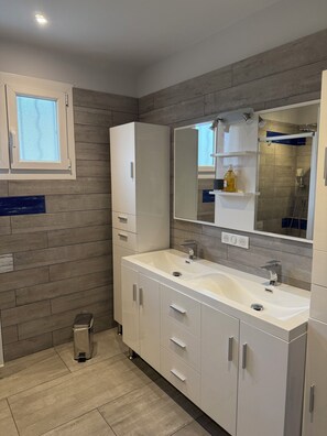 Uma casa de banho moderna com duas pias, um espelho grande e uma janela.