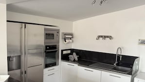 A modern kitchen with stainless steel appliances, a black countertop, and a built-in washing machine. - Villa in Provence (Cavaillon)