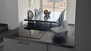 A modern kitchen with a central island, a dining area with chairs, and a view of the outdoors. - Villa in Provence (Cavaillon)