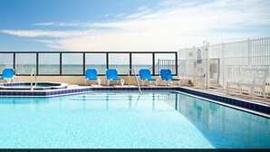 Une piscine avec des chaises bleues et vue sur l’océan.