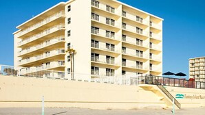 Un hôtel à plusieurs étages doté de balcons, situé près d’une plage.