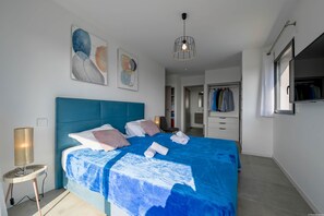 Quarto moderno com cama grande, guarda-roupa e luminária no teto.