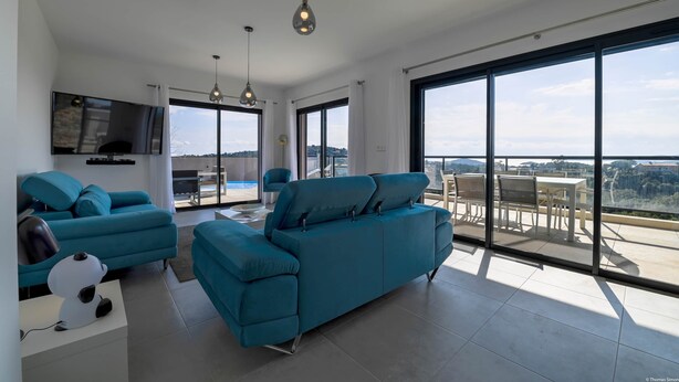 A modern living room with a large sofa, a flat-screen TV, and a dining area with a table and chairs. - Villa U Cousiu (Sainte Lucie De Porto Vecchio)