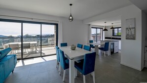 A modern apartment with a dining area, kitchen, and balcony with a city view. - Villa U Cousiu (Sainte Lucie De Porto Vecchio)