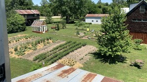 Een landelijk landschap met een kas, houten gebouwen en een verzorgde tuin.