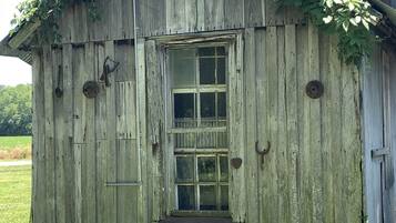 Eine rustikale Holzhütte mit verwitterter Fassade, einem Fenster und einer kleinen Veranda.