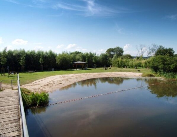 Ein ruhiger Außenbereich mit einer Holterrasse, einem kleinen Teich und einem Gazebo.
