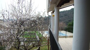 En balkon med udsigt til et træ med hvide blomster, et afspærret område og en pool.