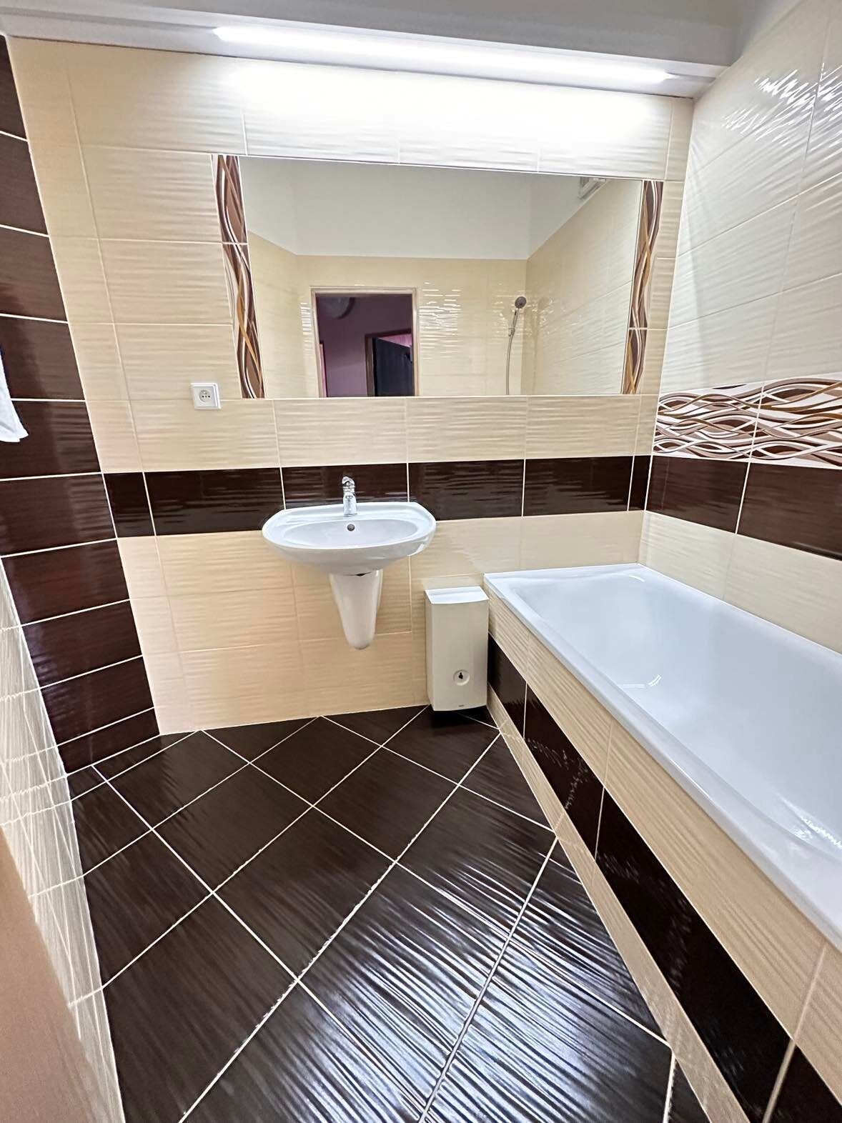 A bathroom with a sink, mirror, and bathtub.