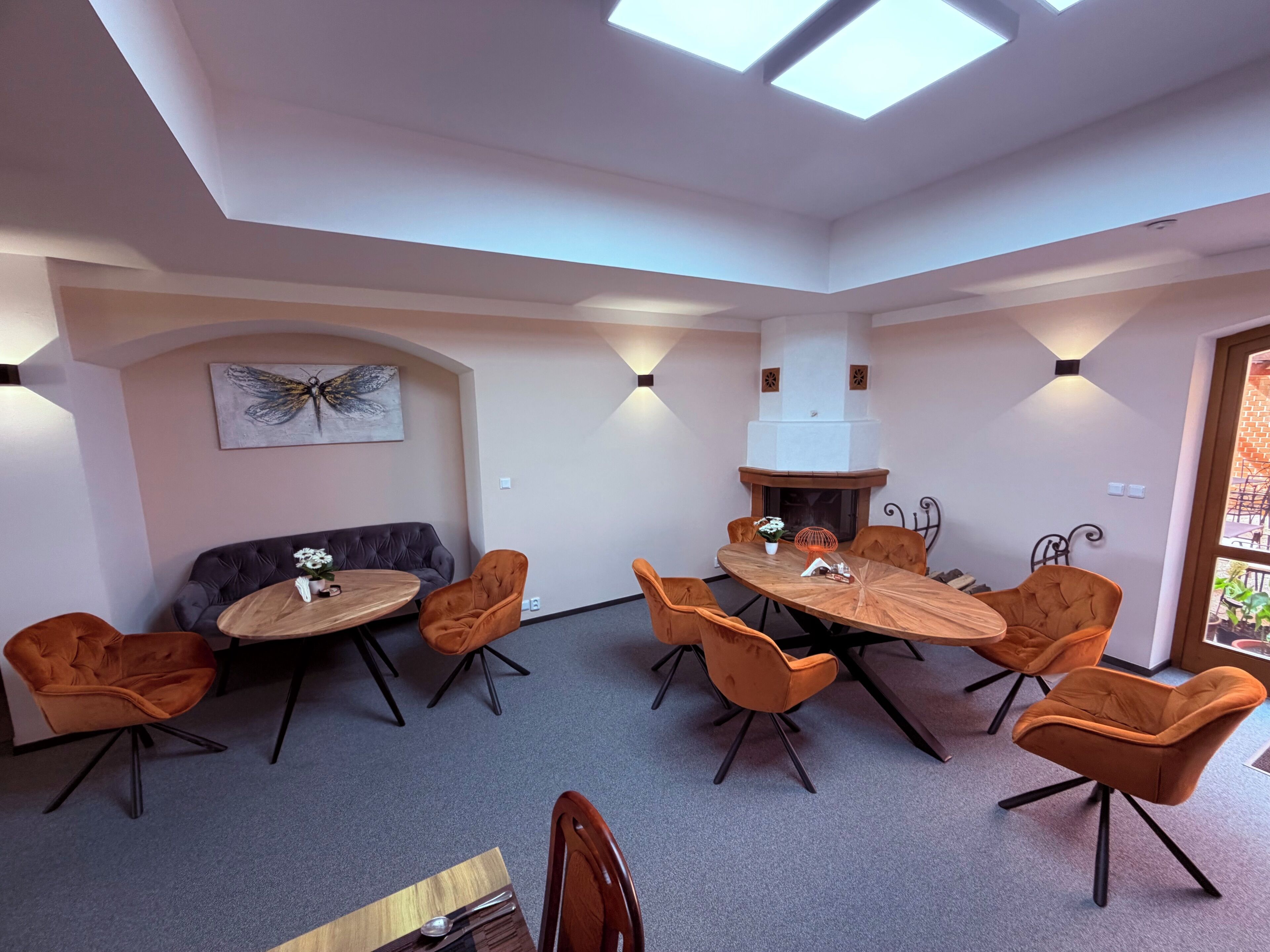 A modern dining area with a round table, multiple chairs, a sofa, and a fireplace.