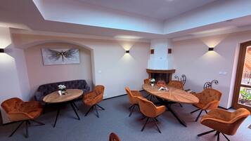 A modern dining area with a round table, multiple chairs, a sofa, and a fireplace.