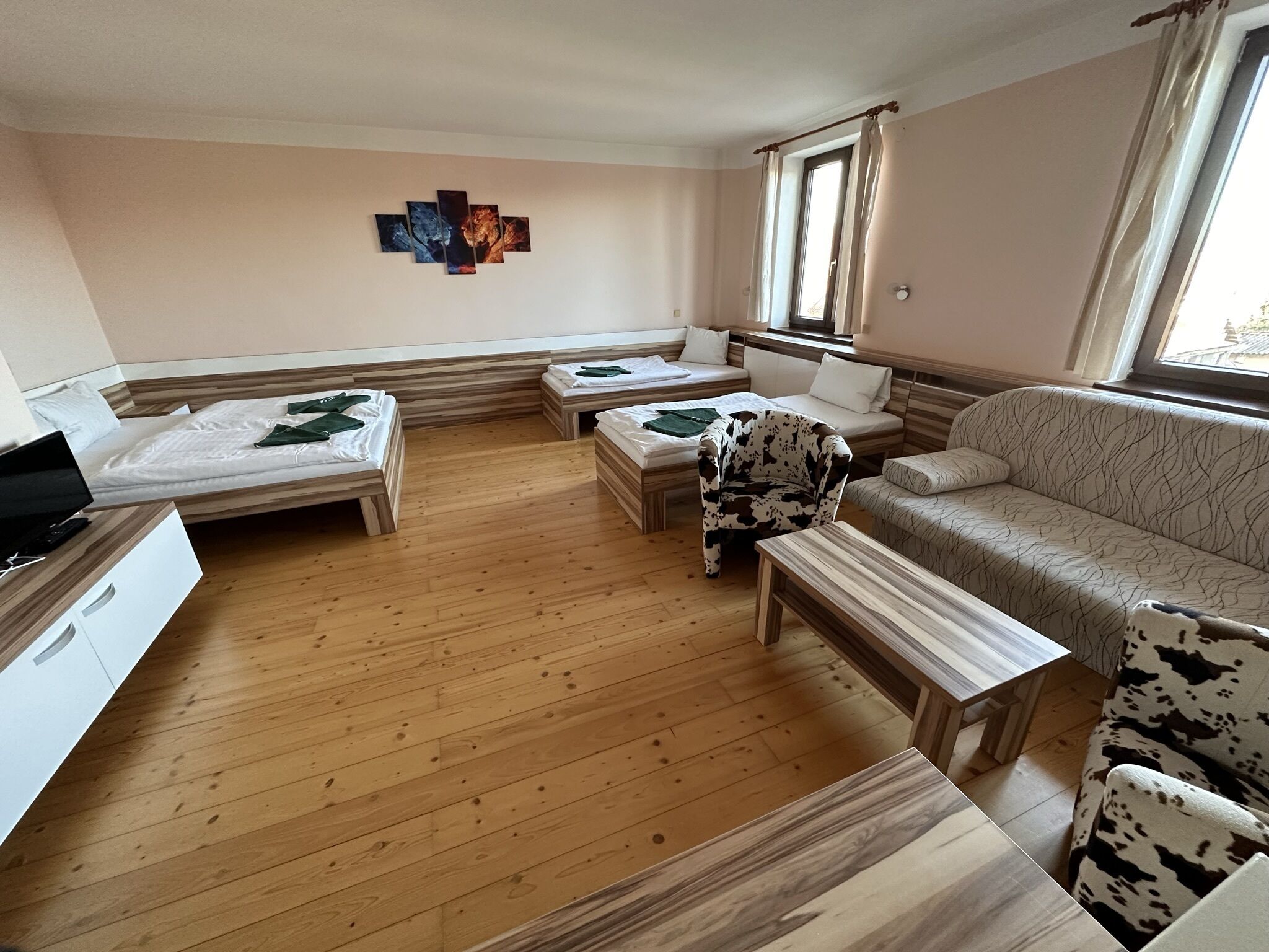 Habitación de hotel con dos camas individuales, un sofá, una mesita y un televisor.