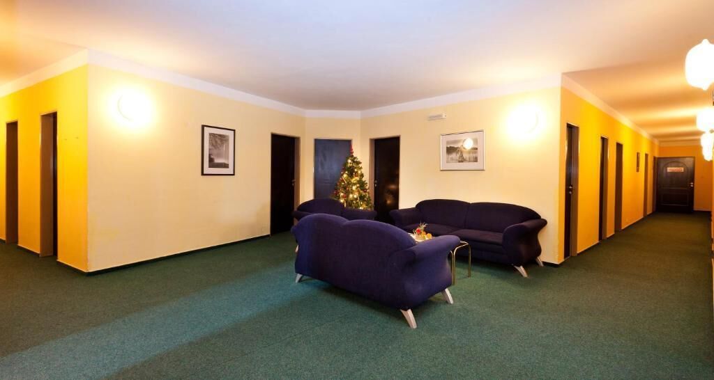 Un hall d’hôtel avec deux canapés, un sapin de Noël et un couloir avec des portes.