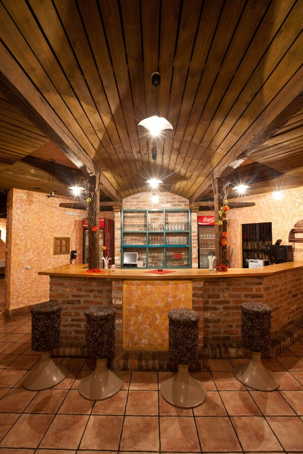 A bar area with a wooden ceiling, brick walls, and a counter with stools.