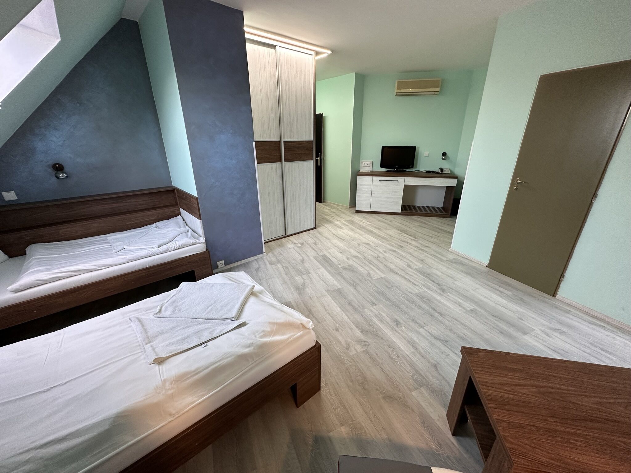Una habitación con dos camas, un escritorio, un televisor y un armario.