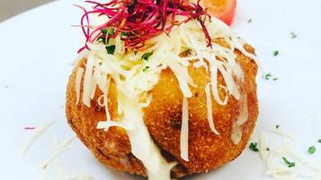 A dish with shredded vegetables, a slice of tomato, and a dollop of sauce on a white plate.