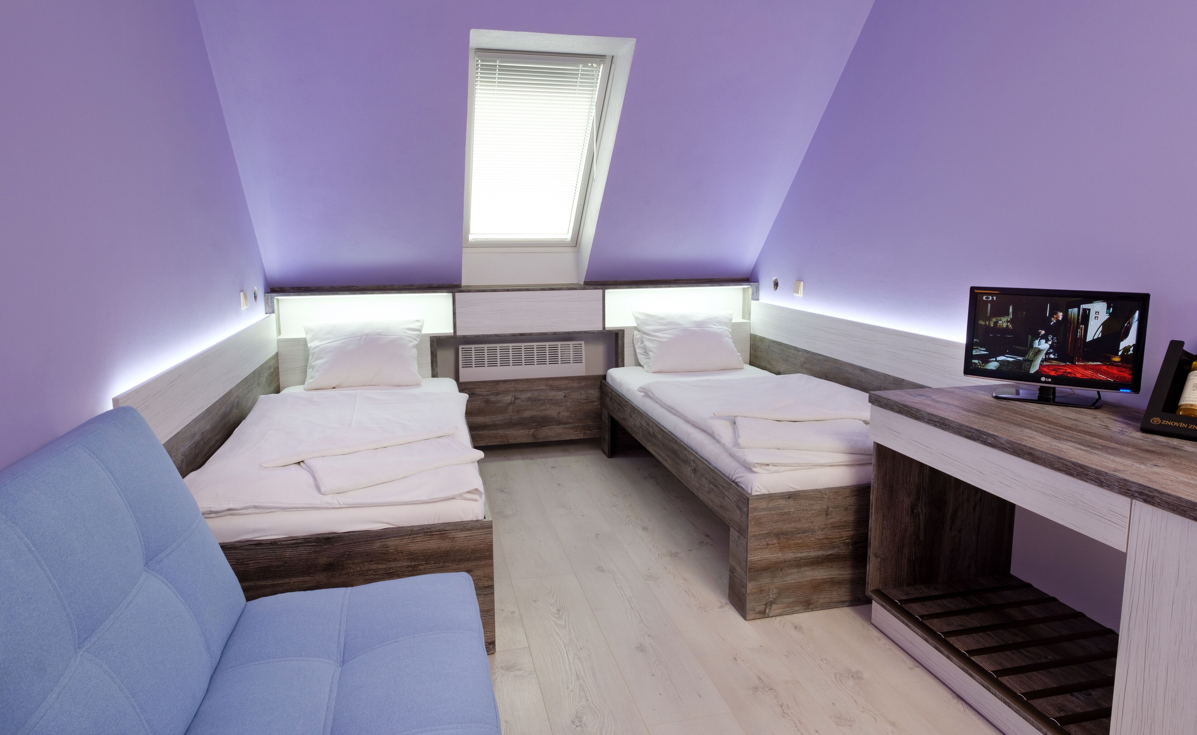 Ein kleines, modernes Schlafzimmer mit zwei Betten, einem Fernseher und einem Fenster.