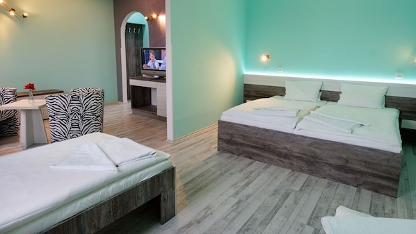 A hotel room with two beds, a TV, a small table with a vase, and a seating area with zebra-patterned chairs.