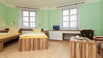 A room with two wooden beds, a small kitchenette, and a seating area with a table and chairs.