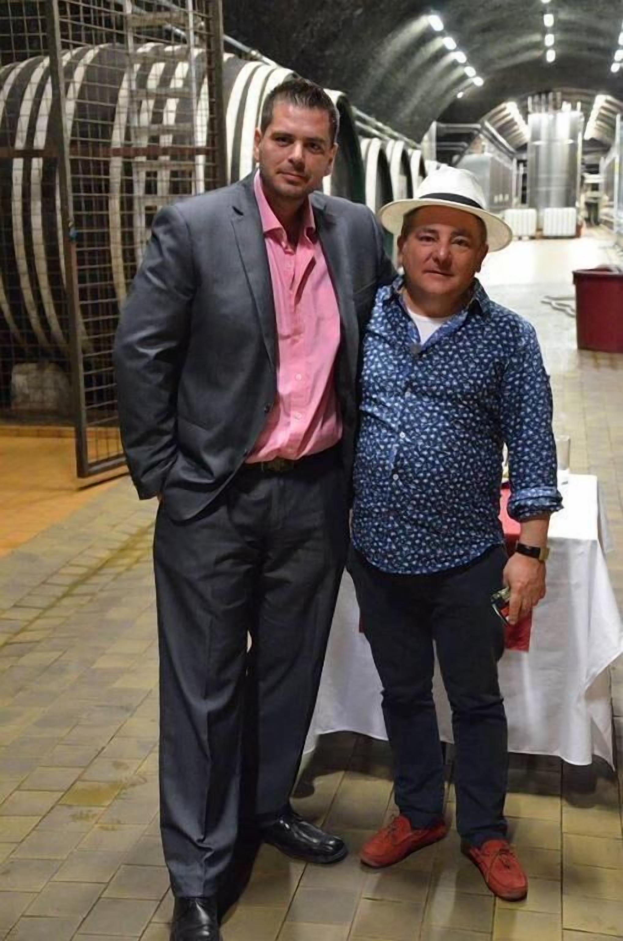 Dos hombres de pie en una habitación con una mesa y sillas.