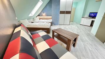 Una habitación compacta con cama elevada, sofá, mesita y televisor.