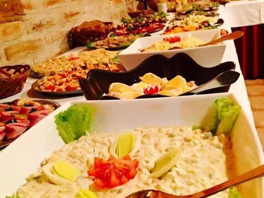 Un bufé con diversos platos, entre ellos ensaladas y aperitivos, en una sala con paredes de piedra y un ambiente rústico.