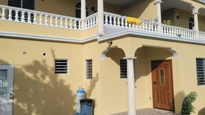 Un bâtiment à deux étages doté d’un balcon, d’une porte en bois et d’une poubelle.