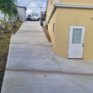 A residential street with a concrete sidewalk, a white door, and a parked white truck.