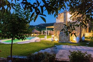 Una villa de piedra con piscina, mobiliario exterior y vistas del paisaje circundante.