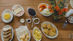 Una mesa de madera con diferentes alimentos para el desayuno, como pan, huevos y frutas.