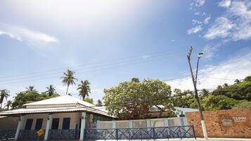 Um edifício com telhado de cerâmica, cerca azul e uma placa com a inscrição