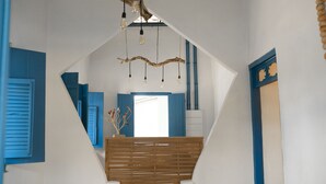 Un interior moderno con techo inclinado, vigas a la vista y una escalera de madera.