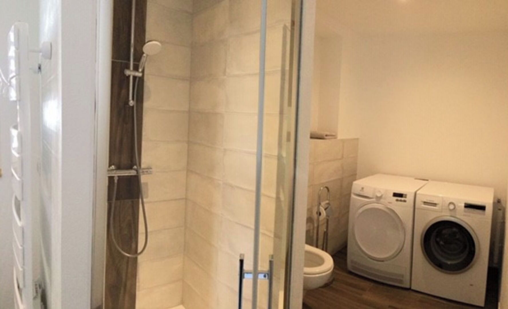 Une petite salle de bain comprenant une douche, des toilettes et un lave-linge.