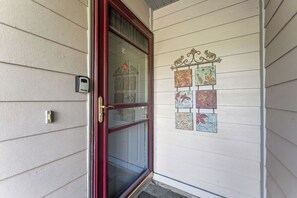 Une porte dotée d’un panneau de verre et d’un cadre rouge, une sonnette et un panneau décoratif fixé au mur, orné de motifs floraux.
