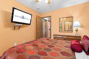 A hotel room with a bed, a television mounted on the wall, a dresser, a mirror, and a lamp. - Best-View 3-Bedroom Condo, Close to Silver Dollar City with Free Tickets & Outdoor Pool (Branson)